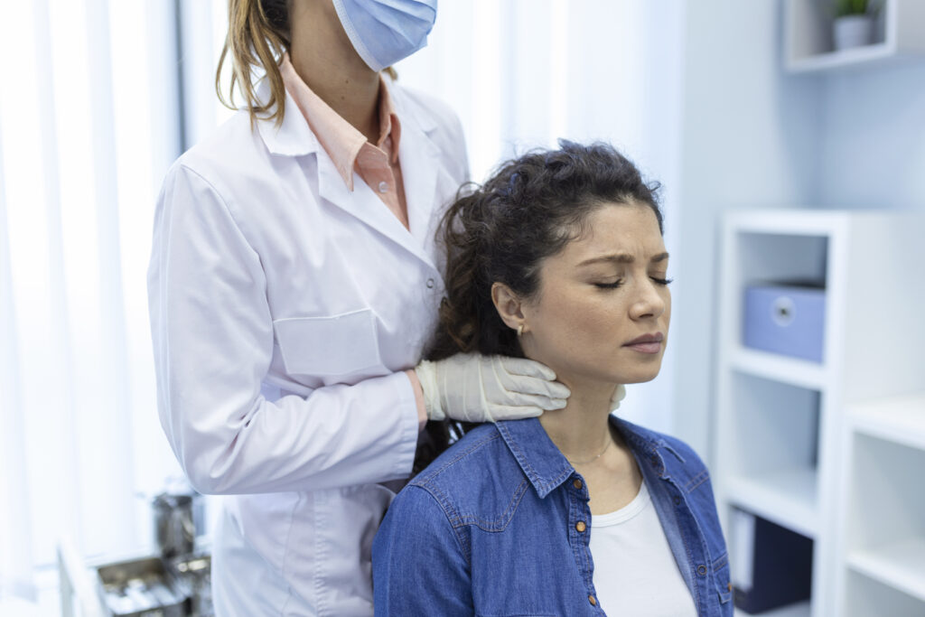endocrinologist examining throat of young woman in clinic. women with thyroid gland test . endocrinology, hormones and treatment. inflammation of the sore throat