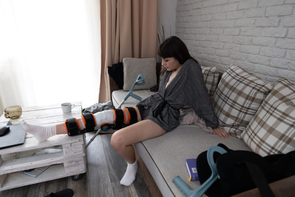 Person sitting on couch in full-leg brace after ACL repair