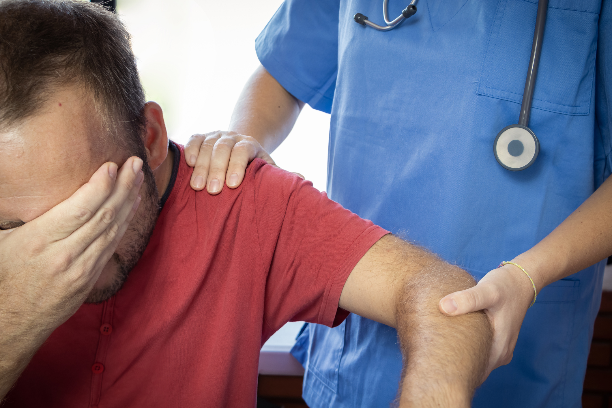 Medical provider guiding man’s dislocated shoulder back into place
