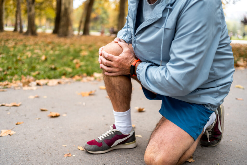 Runner squatting on pavement and grabbing knee