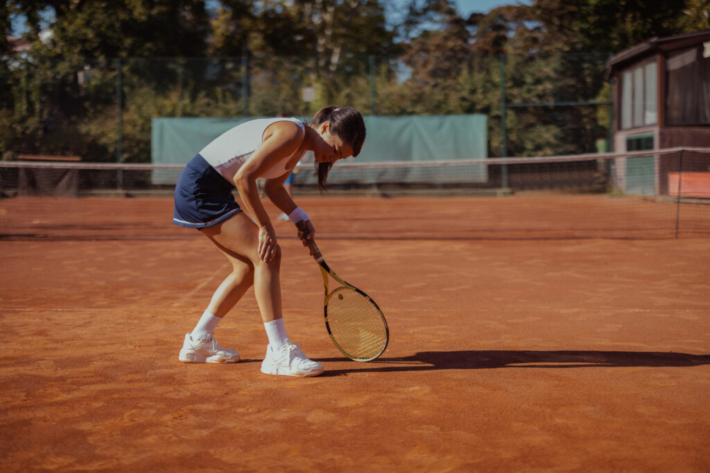 Tennis player grabbing knee on tennis court