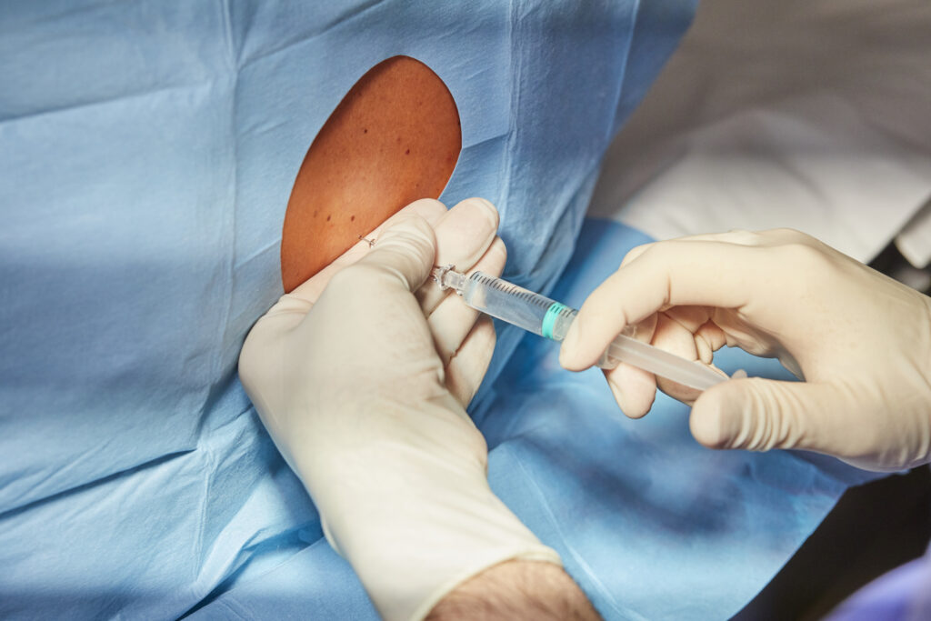 Doctor performing non-surgical spinal injection on patient