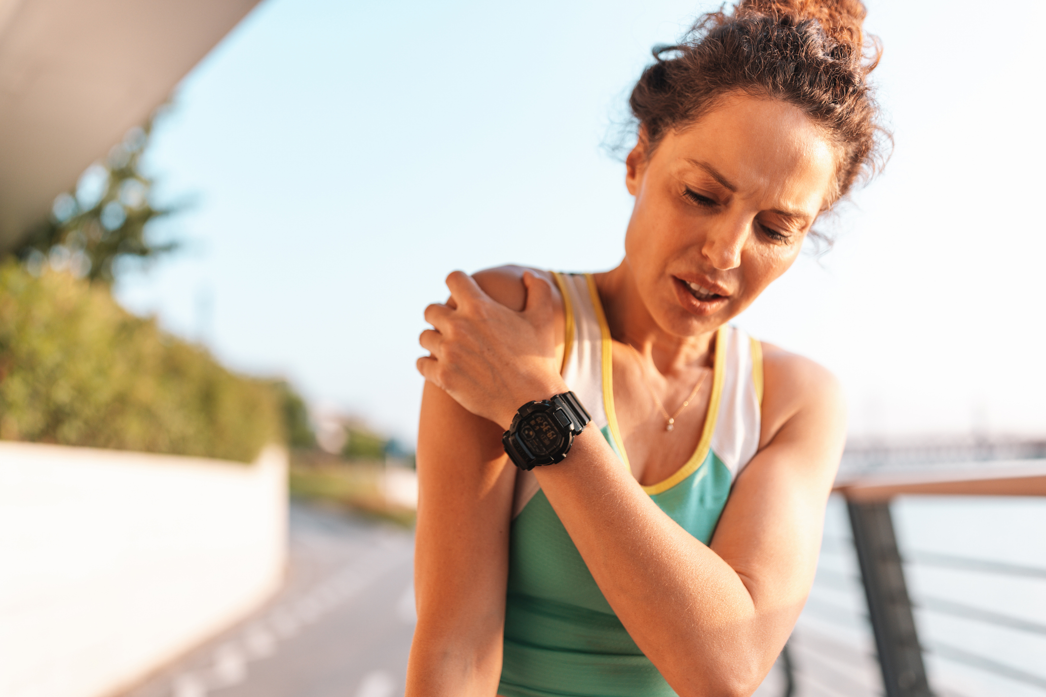 Athlete holding shoulder in pain while exercising outside