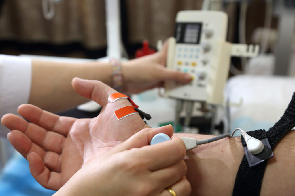 Doctor performing diagnostic EMG on patient’s hand