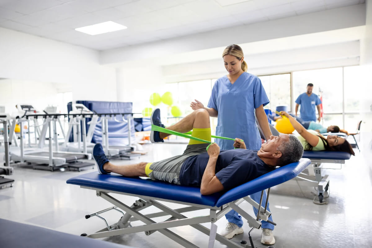 Person doing guided exercise with resistance band with help from physical therapist