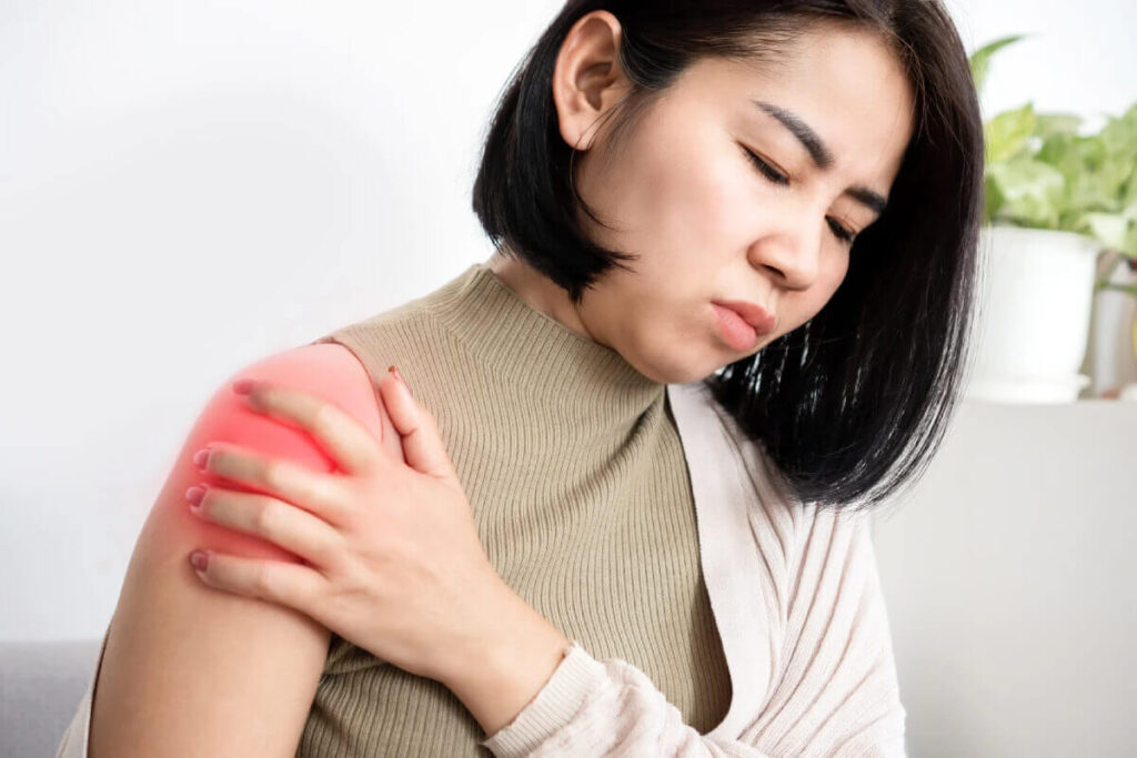 Woman holding shoulder in pain with red highlighted area